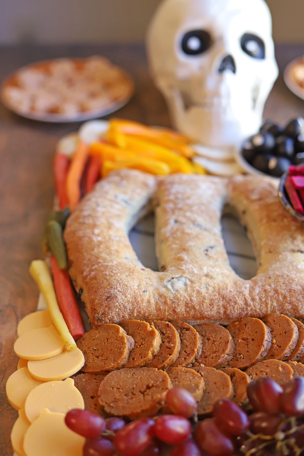 Cheddar pumpkins, grapes, and vegan pepperoni on skeleton charcuterie board with fougasse.