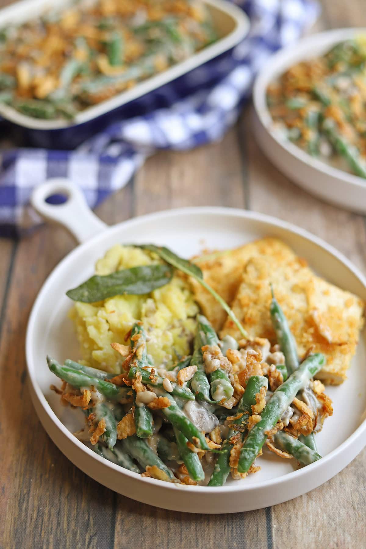 Dairy-free green bean casserole on plate with mashed potatoes and breaded tofu.
