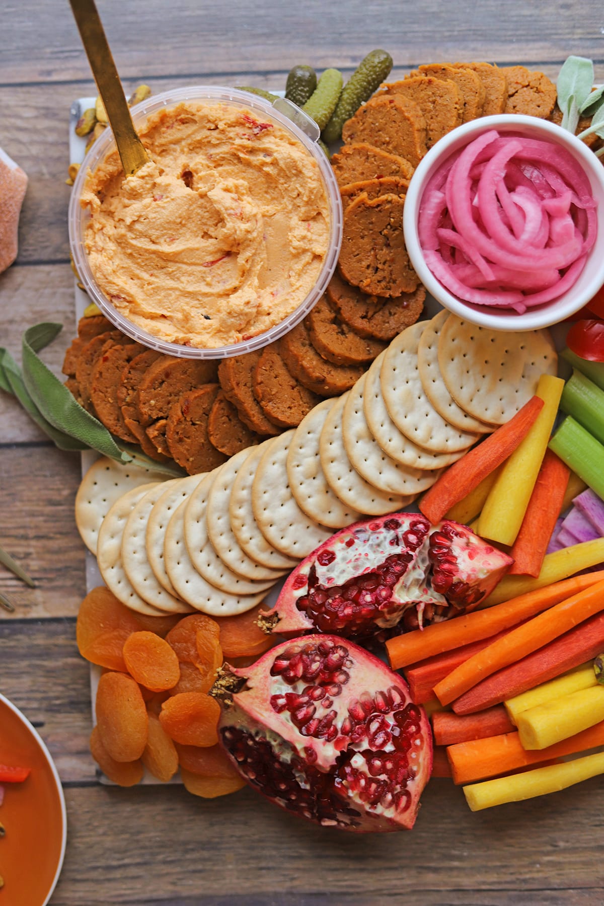 Vegan pimento cheese, pickled onions, vegan pepperoni, pomegranate, and veggies on Thanksgiving charcuterie board.
