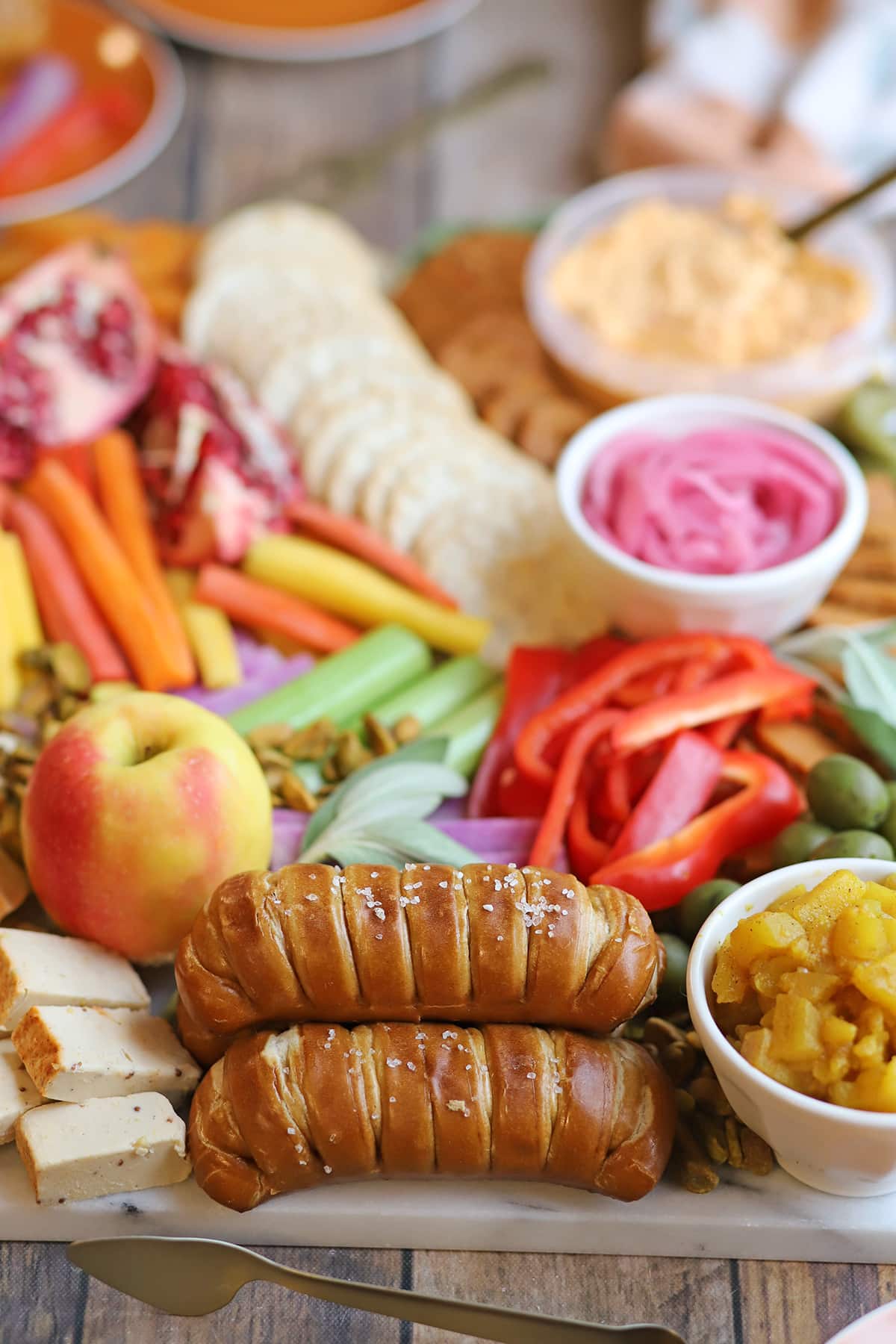 Vegan Thanksgiving charcuterie board with pretzel bread, apple, veggies, apple chutney, crackers, and vegan pepperoni.
