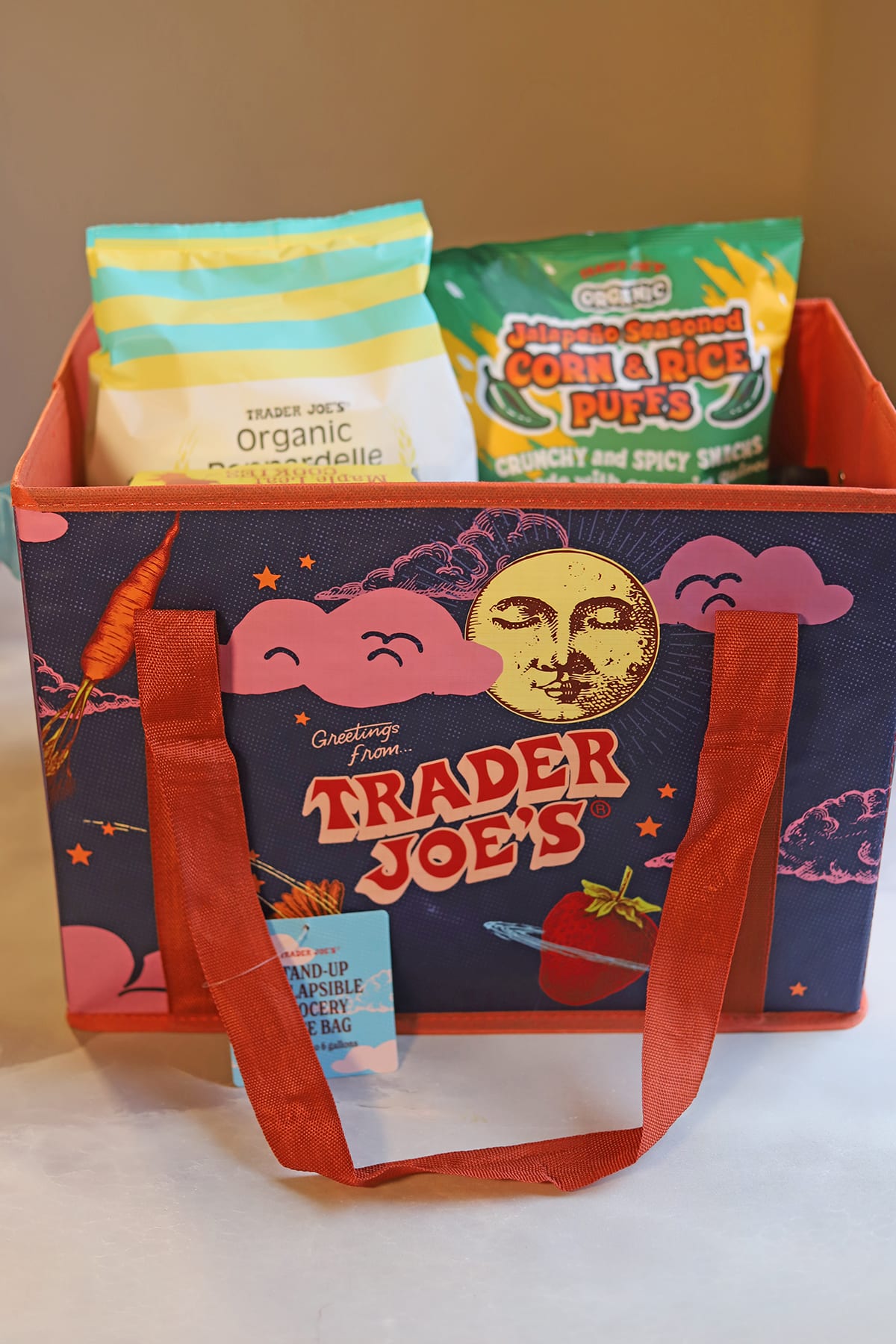 Blue collapsible Trader Joe's bag with snacks and groceries for white elephant gift exchange.