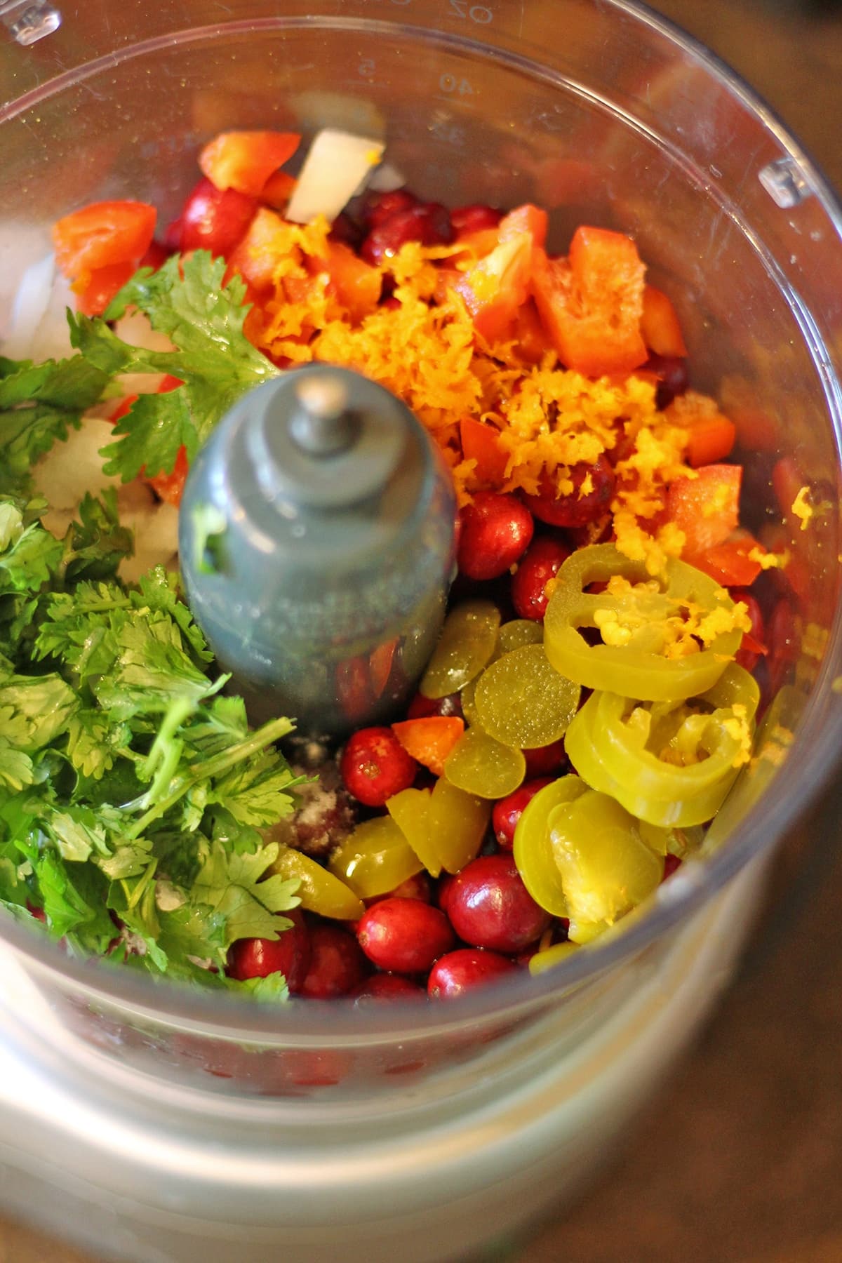 Jalapenos, cranberries, orange zest, cilantro, and red bell pepper in food processor bowl.