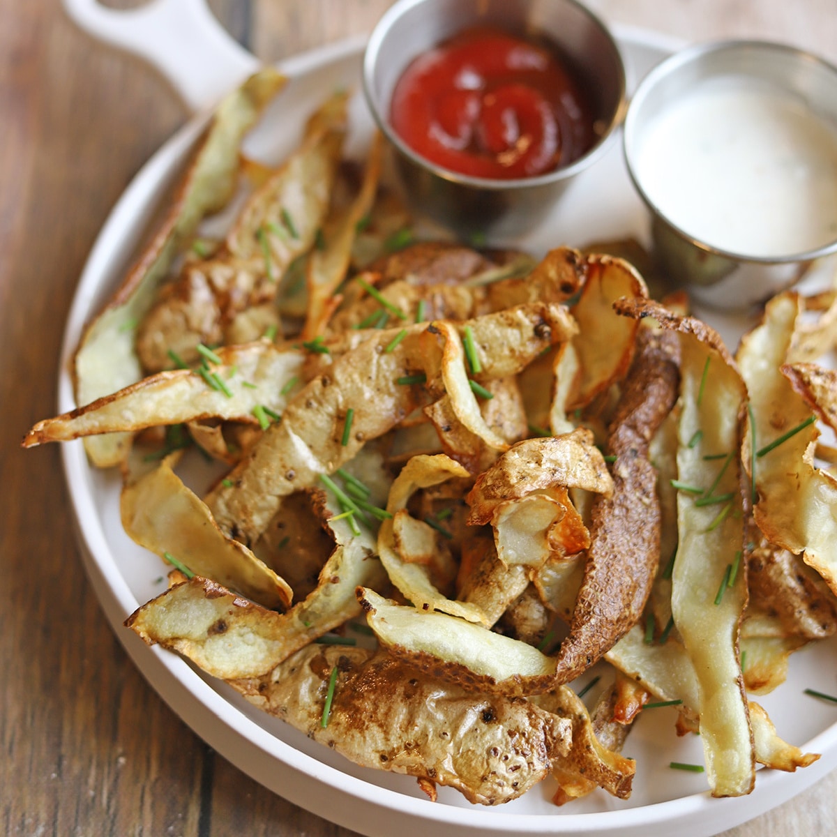 Crispy air fried potato peels on plate with dipping sauces.