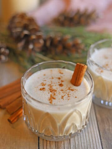 Glass of vegan eggnog on table with cinnamon.
