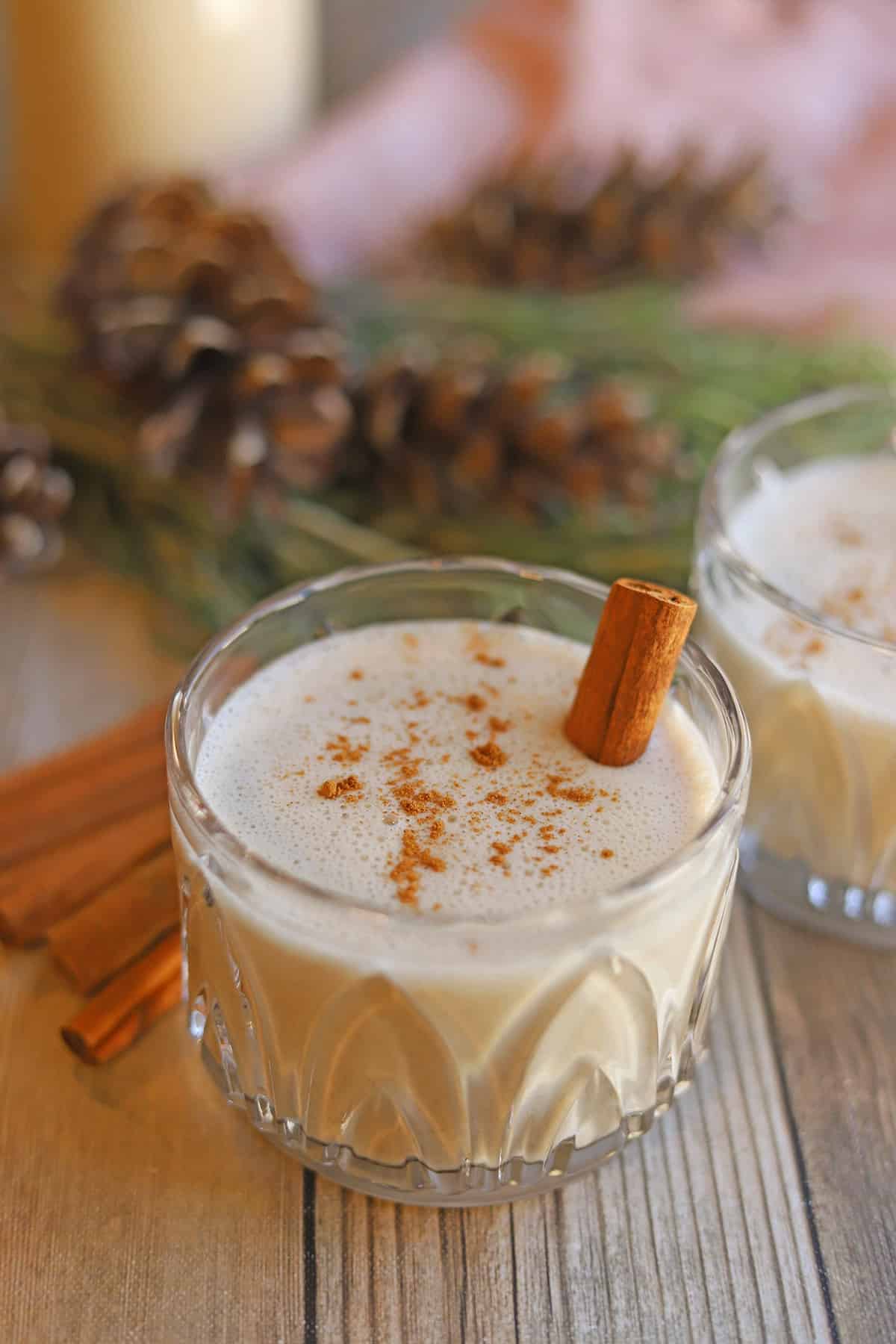 Glass of vegan eggnog on table with cinnamon.