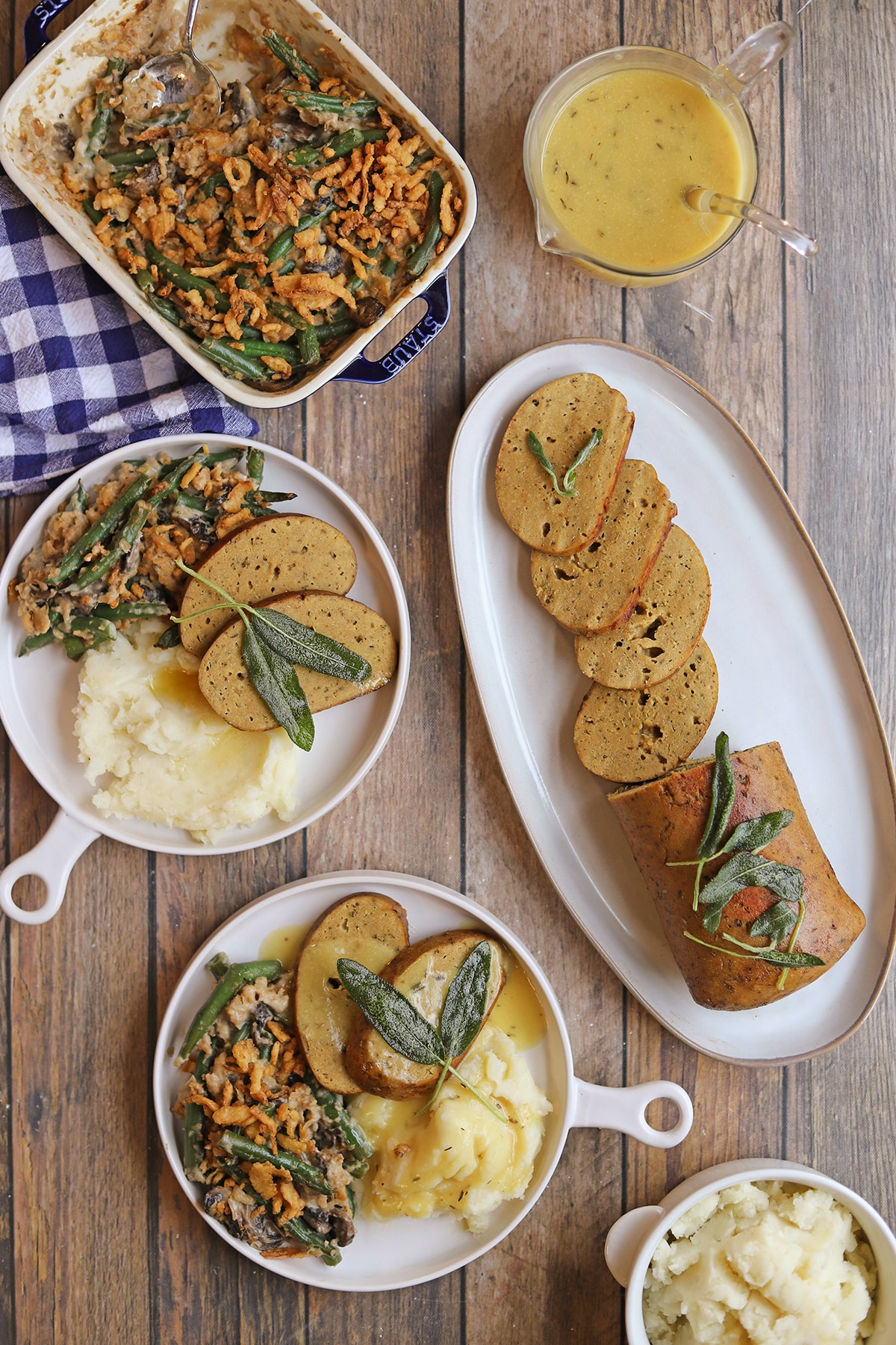 Thanksgiving dinner spread with vegan roast turkey, green bean casserole, mashed potatoes, and gravy.