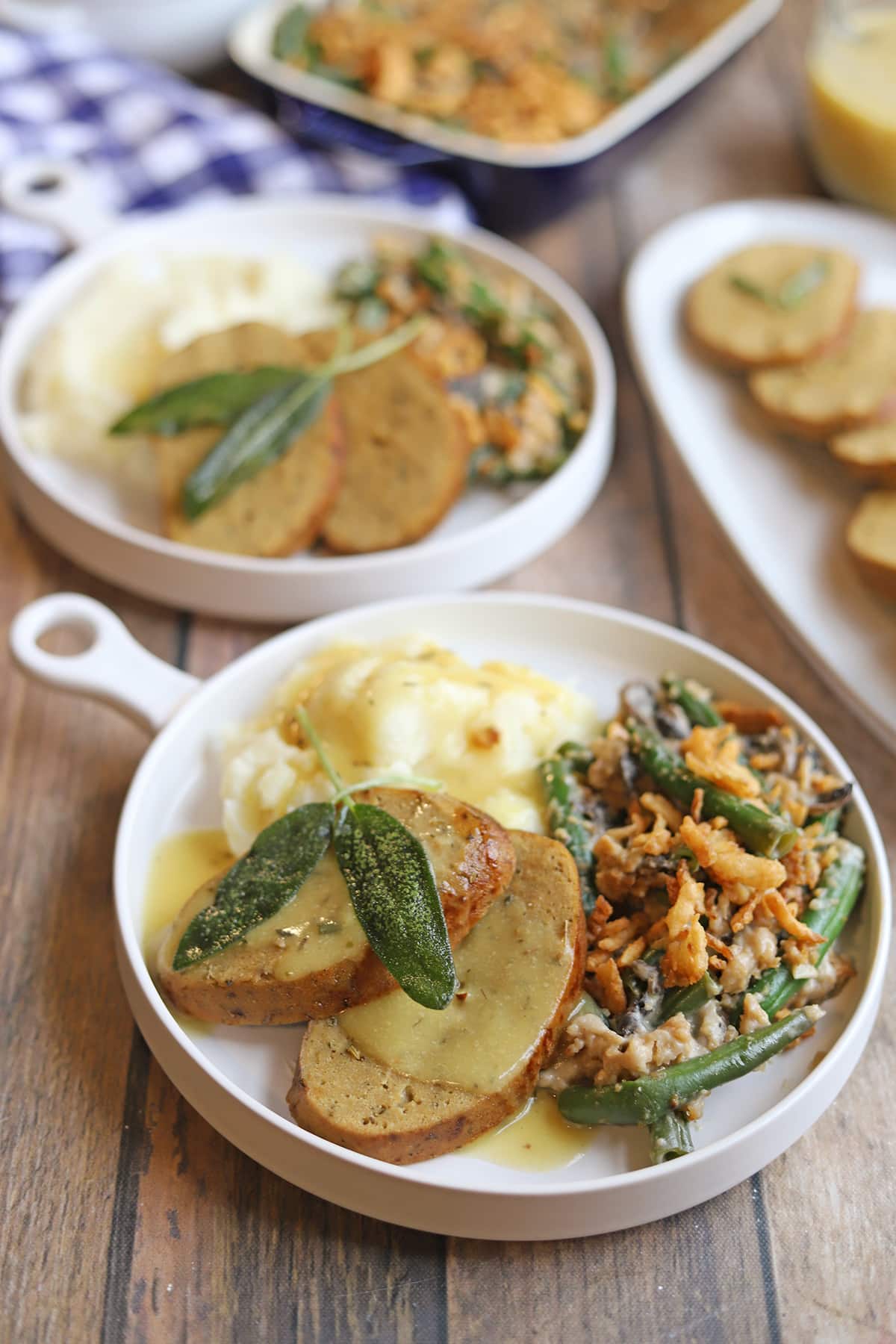 Slices of vegan turkey roast on plate with mashed potatoes and green bean casserole.