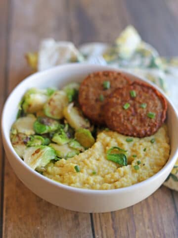 Vegan grits breakfast bowl with meatless sausage and Brussels sprouts.