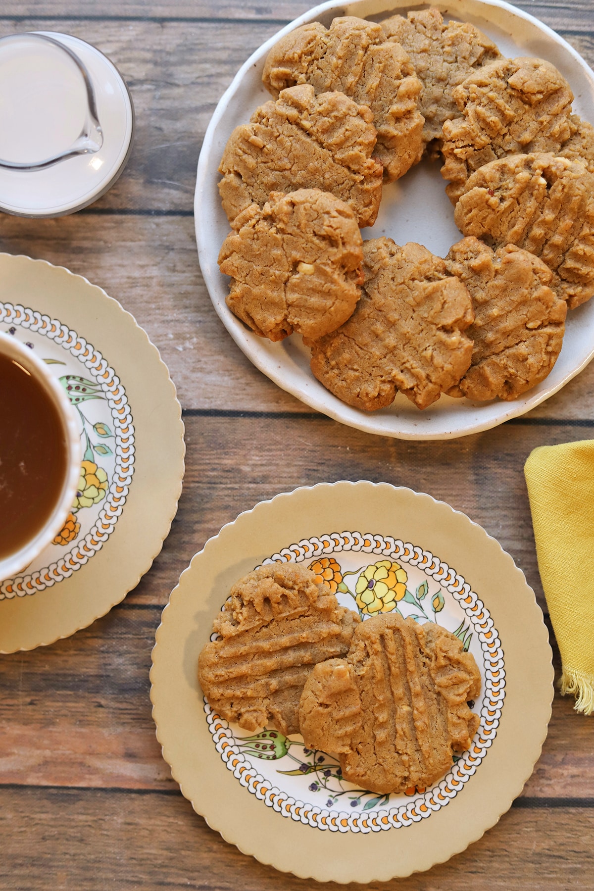 Peanut butter cookies on platter and plate by tea and non-dairy milk.