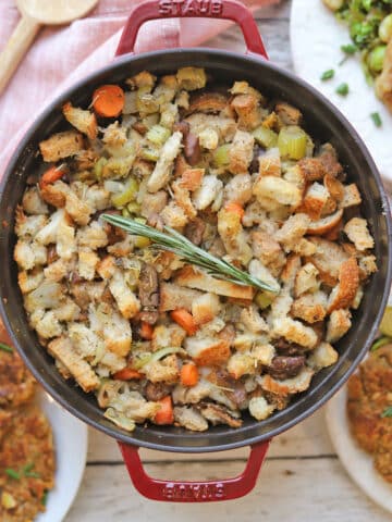 Vegan stuffing in dutch oven with rosemary garnish.