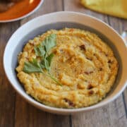 Creamy vegan polenta with sun-dried tomatoes and garlic in bowl.