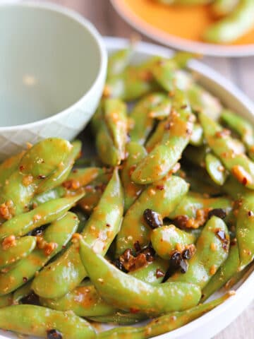 Close-up crunchy bits of chili crisp and garlic sauce coating steamed edamame.