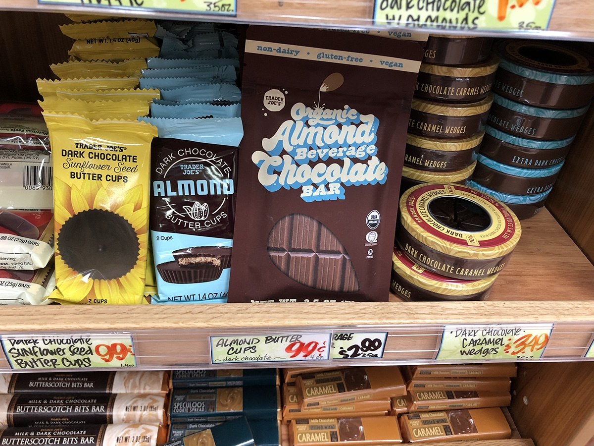 Organic almond beverage chocolate bar on store shelf with dakr chocolate sunflower seed butter cups, and dark chocolate almond butter cups.