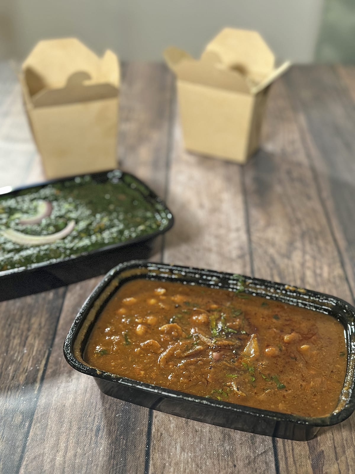 Takeout containers of chana masala, saag Beyond Chicken, and rice.