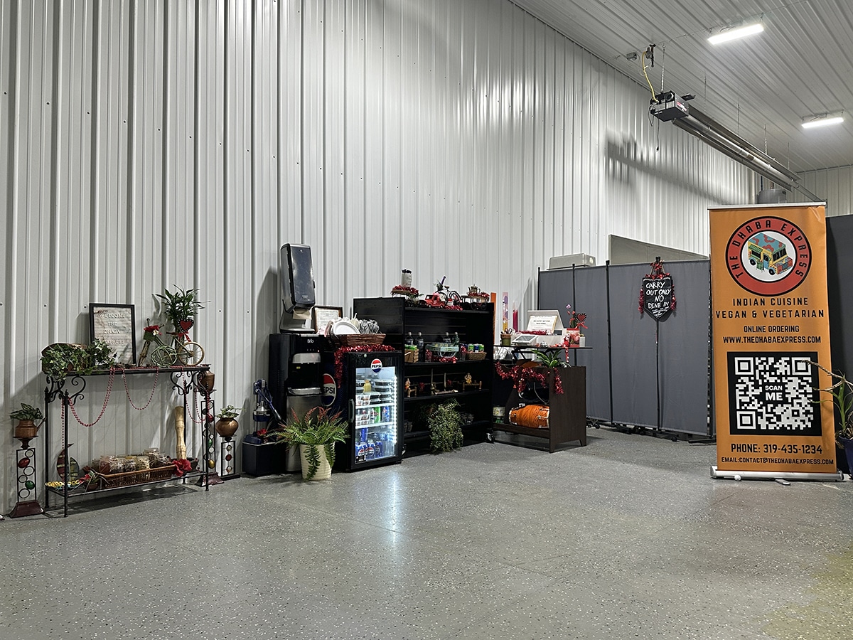 Checkout counter with drinks in mini refrigerator and banner with QR code at Dhaba Express in Tiffin, Iowa, outside of Iowa City.