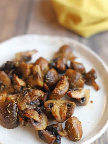 Perfectly roasted air fryer mushrooms with herbs and garlic on plate.