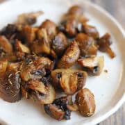 Close-up roasted air fryer mushrooms sprinkled with herbs and garlic.