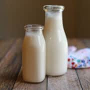 Two bottles of homemade almond milk on table with colorful napkin.