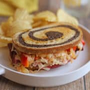 Vegan reuben sandwich with peppers, onions, and Thousand Island on rye with potato chips.