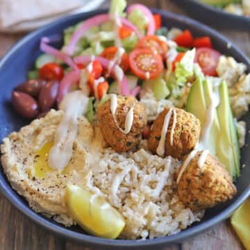 Falafel bowl with rice, hummus, salad, kalamata olives, and lemon.