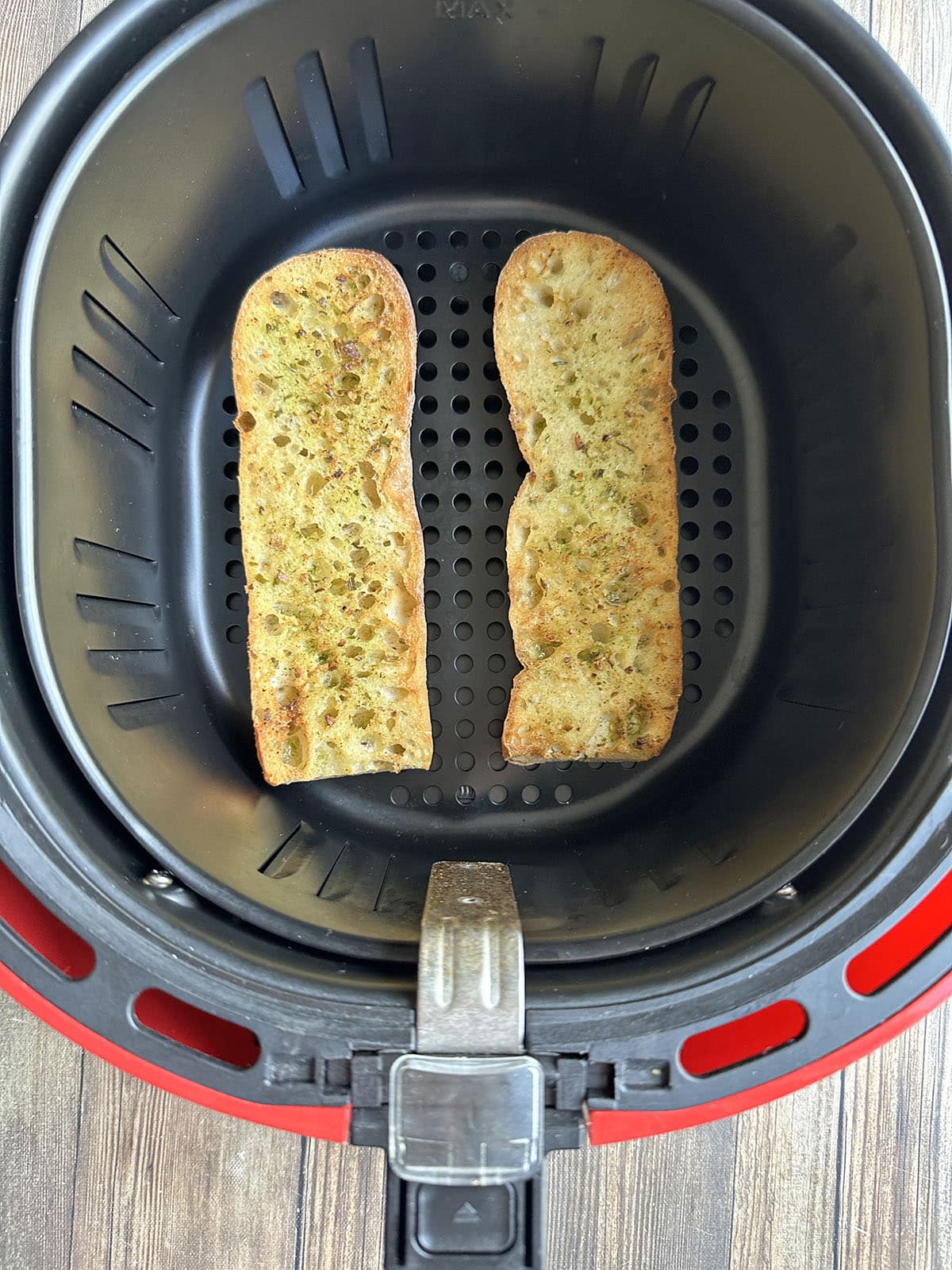 Toasted baguette with onion salt seasoning in air fryer basket.