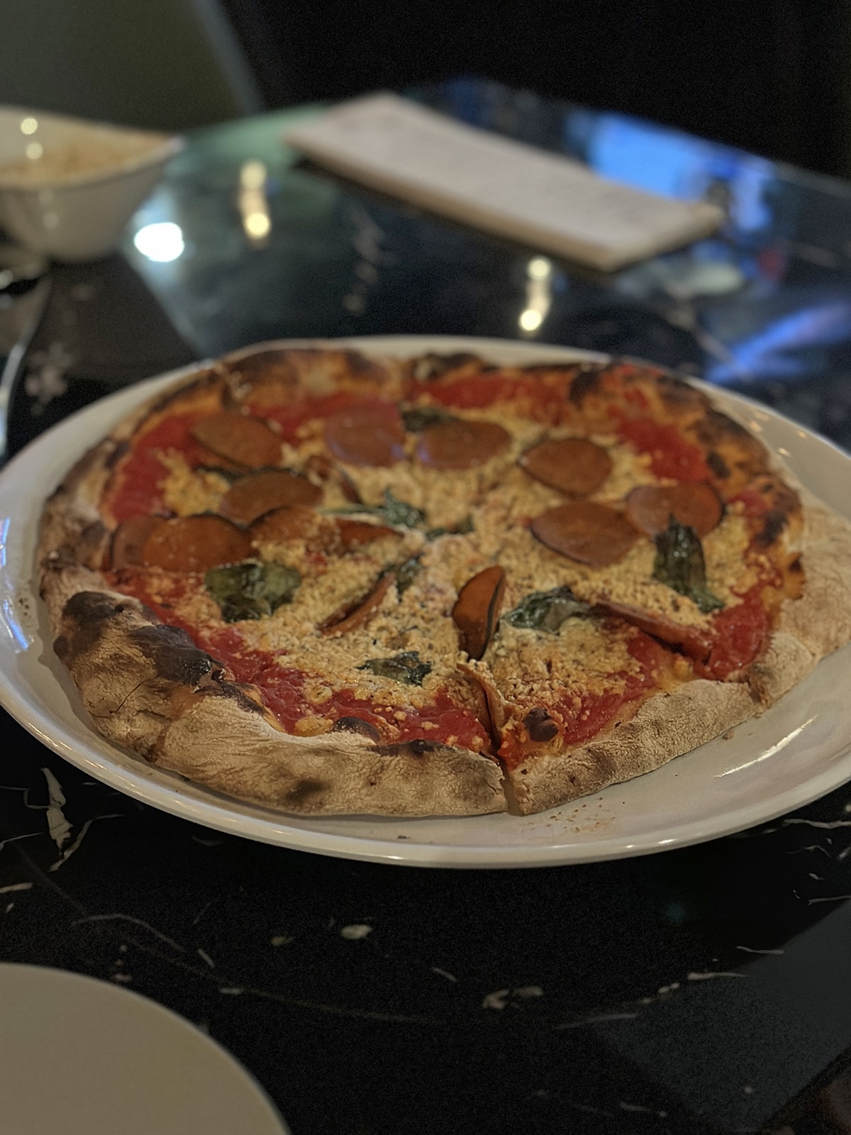 Vegan pepperoni pizza at Basil and Vine in the Quad Cities with vegan mozzarella, fresh basil, and marinara.