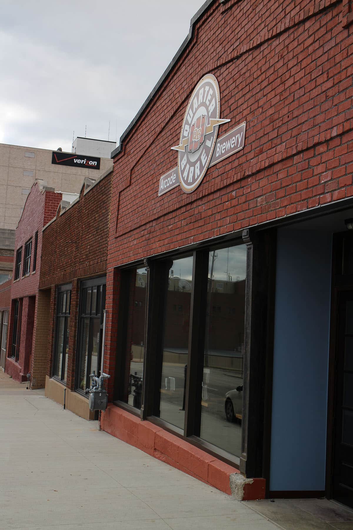 Exterior brick building with sign that says, "Quarter Barrel arcade brewery."