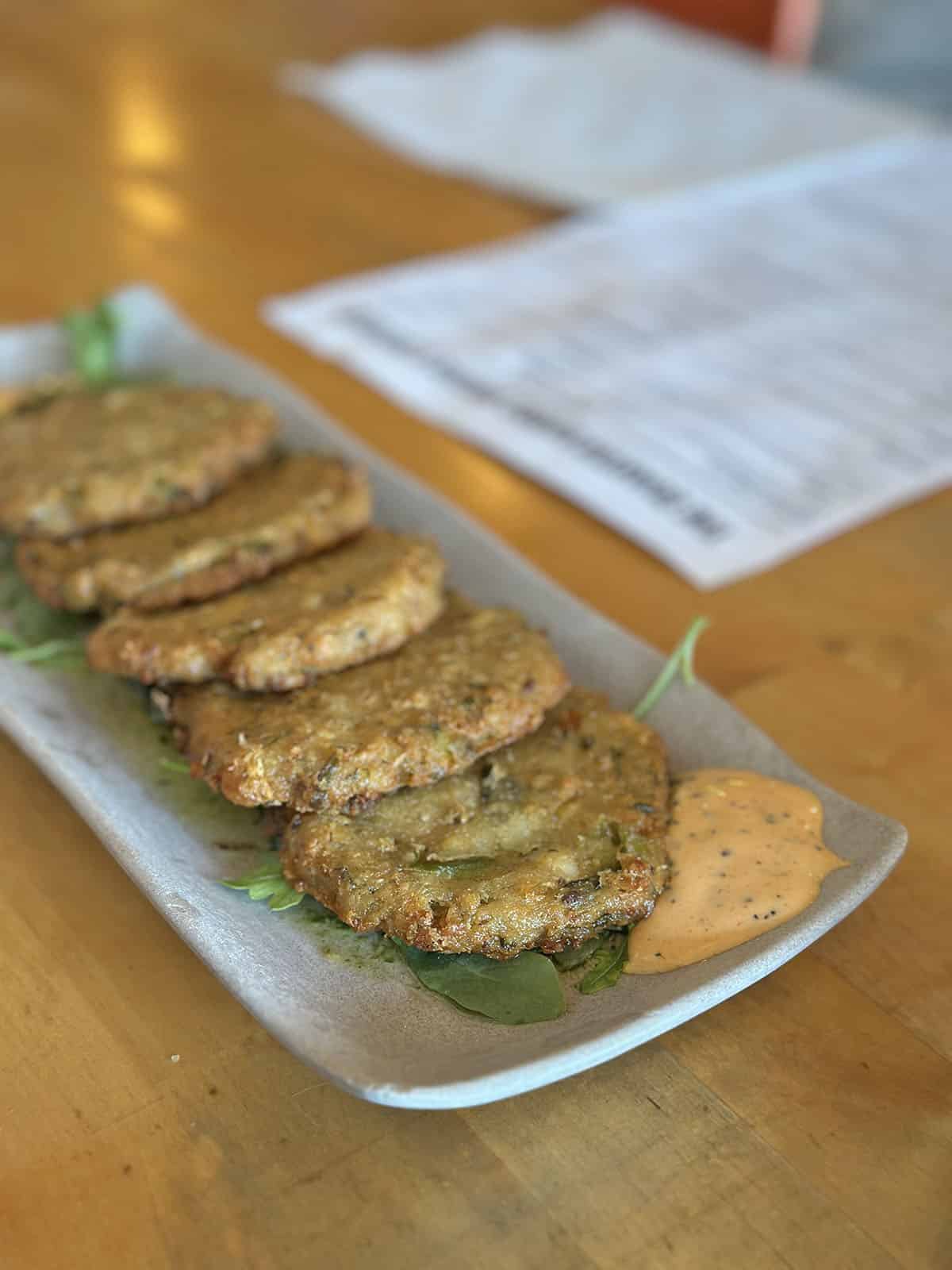 Fried falafel patties with dipping sauce on plate.