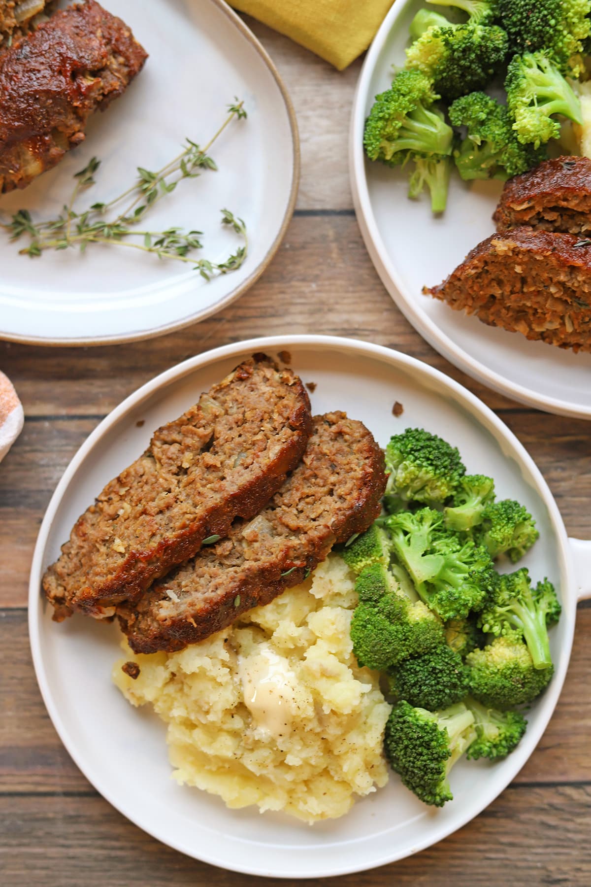 Plant-based meatloaf main course on plates with mashed potatoes and broccoli.