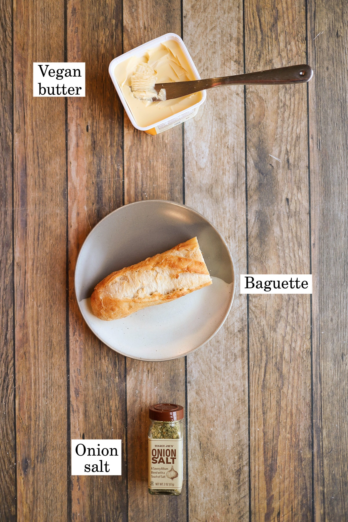 Labeled ingredients for air fryer garlic bread: vegan butter, baguette, and onion salt.