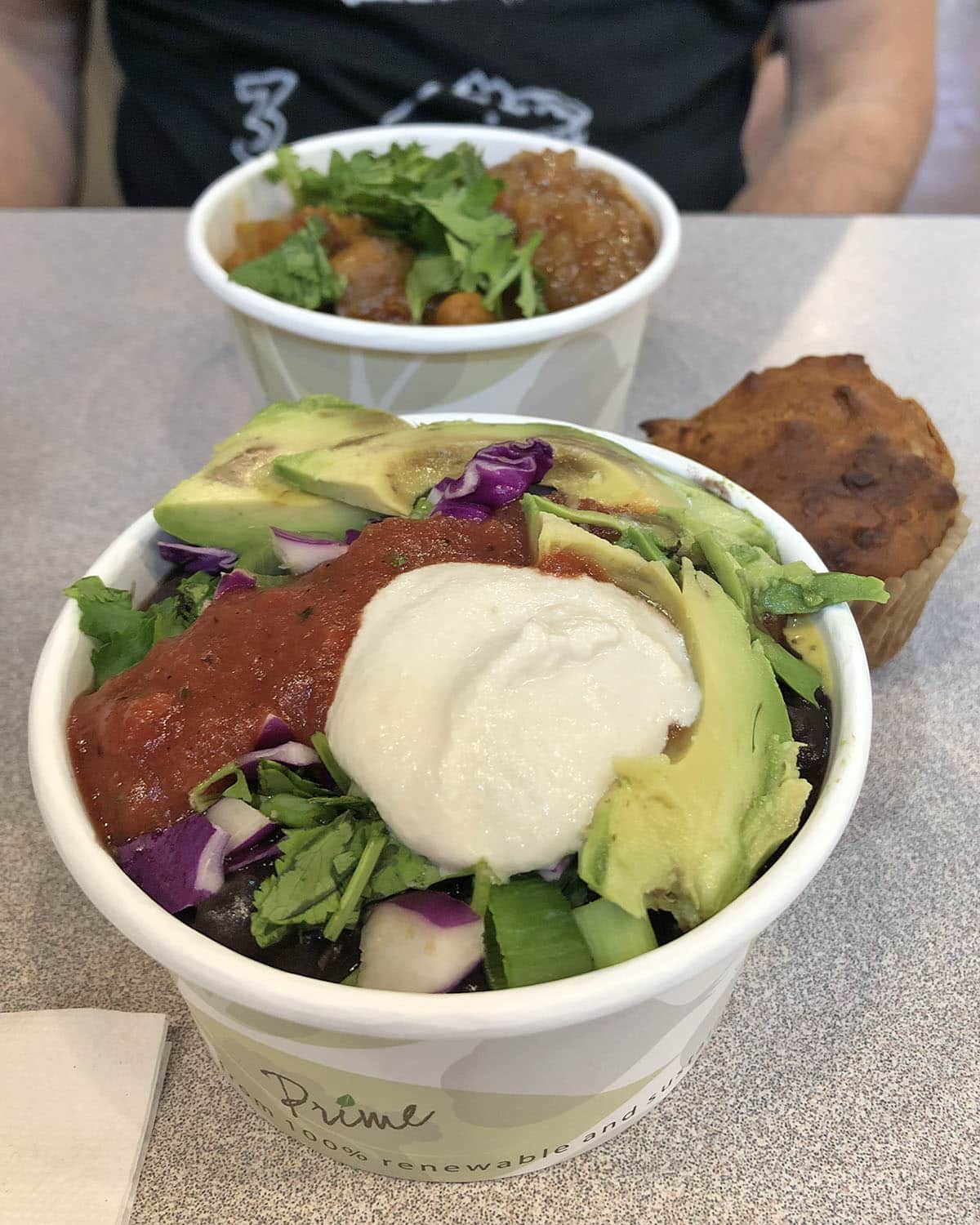 Bowl with beans, vegan sour cream, salsa, avocado, and veggies on table with mango chutney bowl and muffin in Cedar Rapids, Iowa.