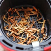 Crispy strips of wonton wraps in air fryer basket.