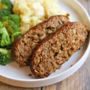 Moist slices of vegan meatloaf made with Impossible meat on plate with mashed potatoes and broccoli.