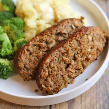 Moist slices of vegan meatloaf made with Impossible meat on plate with mashed potatoes and broccoli.
