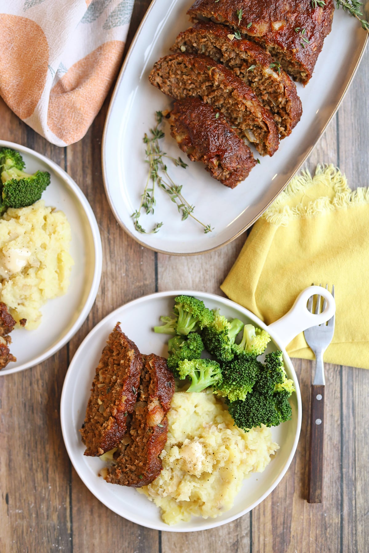 Vegan meatloaf dinner with mashed potatoes and broccoli on plates.