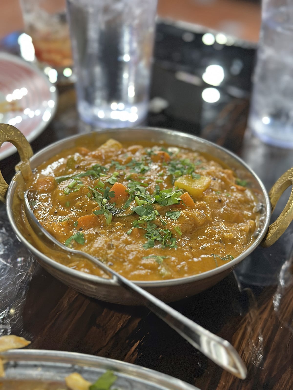 Vegetable chettinad curry with cilantro garnish in kadhai with spoon.