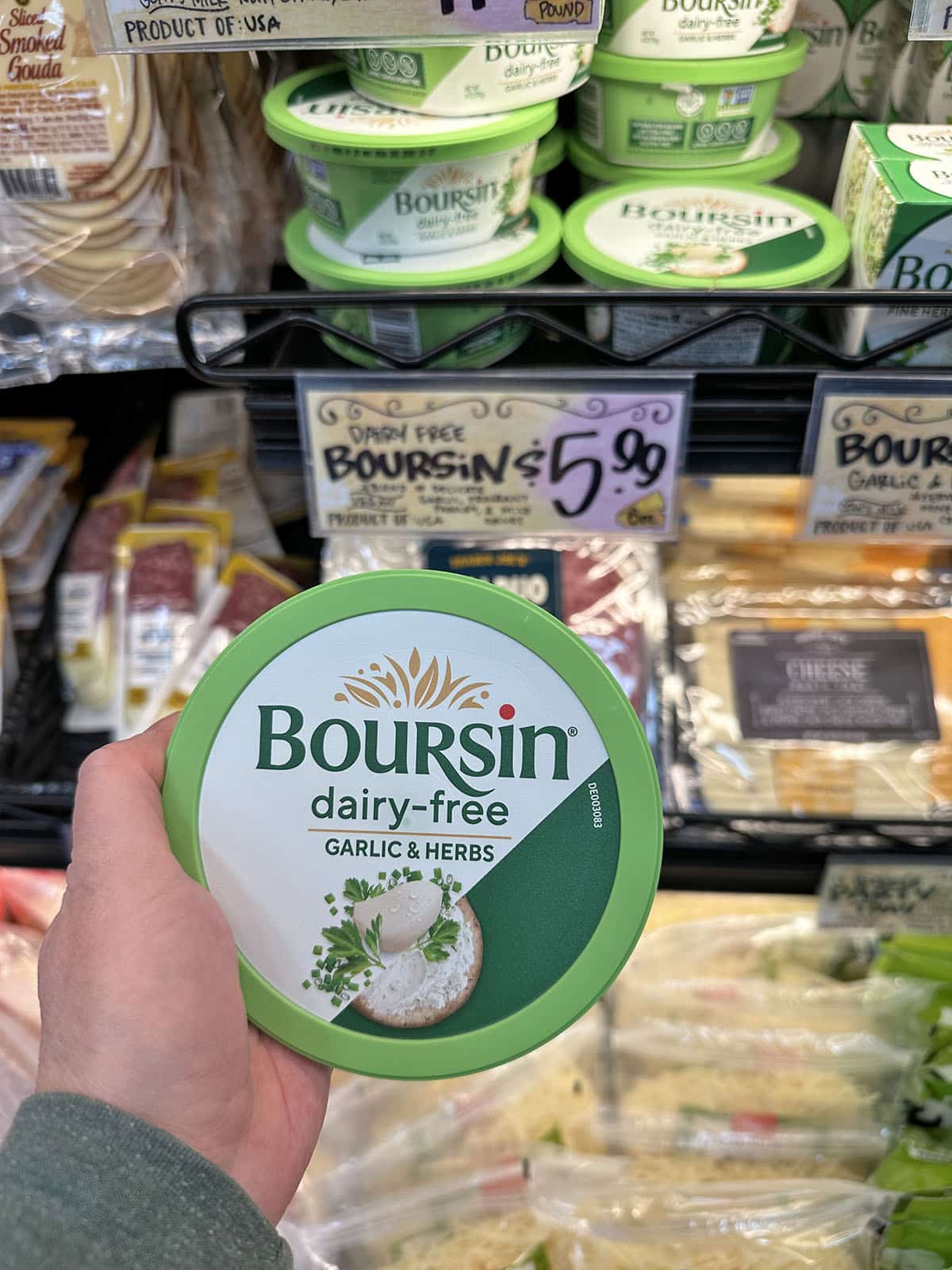 Hand holding container of dairy-free Boursin with garlic and herbs at Trader Joe's.