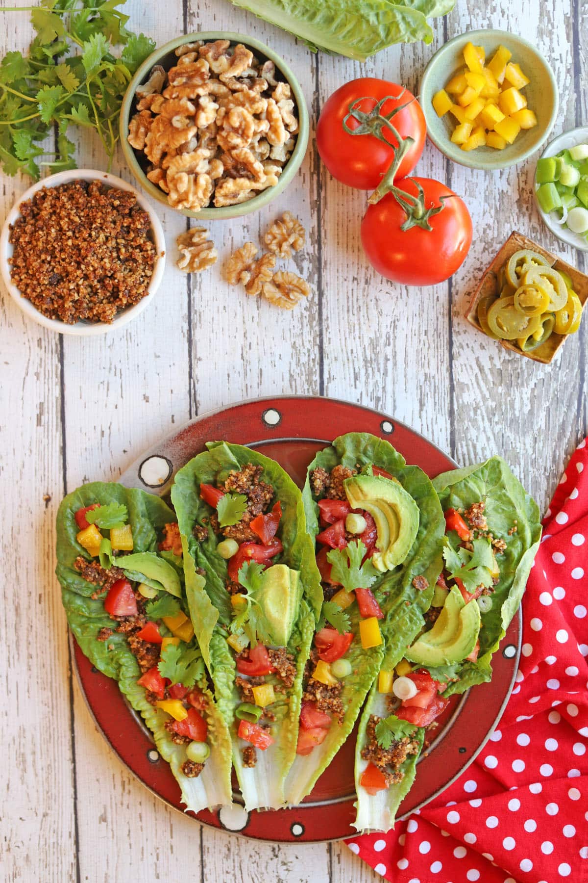 Vegan raw tacos with walnut filling, tomatoes, bell pepper, green onion, and tomatoes.
