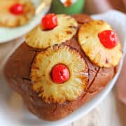 Broiled pineapple rings with maraschino cherries on vegan ham, glazed in pineapple brown sugar glaze.