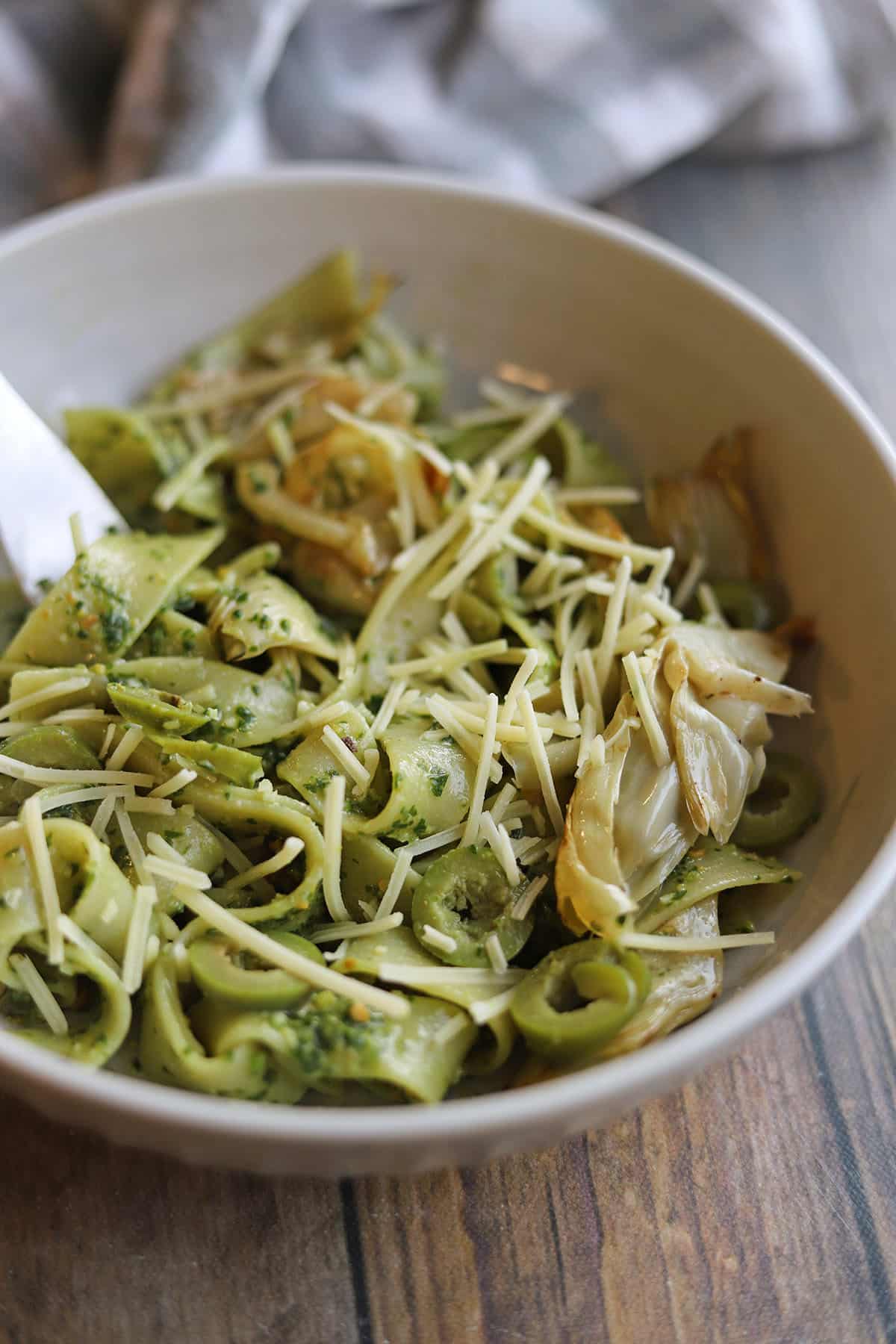 Pappardelle tossed in pesto with artichokes, olives, and Trader Joe's vegan parmesan cheese.