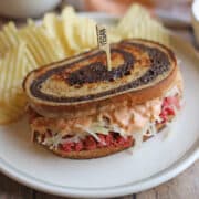 Vegan corned beef jackfruit reuben sandwich on plate with potato chips.