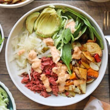 Vegan reuben bowl with sauerkraut, corned jackfruit, roasted potato hash, baby spinach, and avocado.
