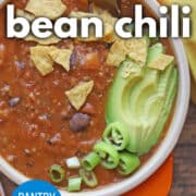 Text overlay: 3 bean chili, pantry friendly, cadryskitchen.com. Vegan chili topped with avocado, green onions, peppers, and crushed tortilla chips.