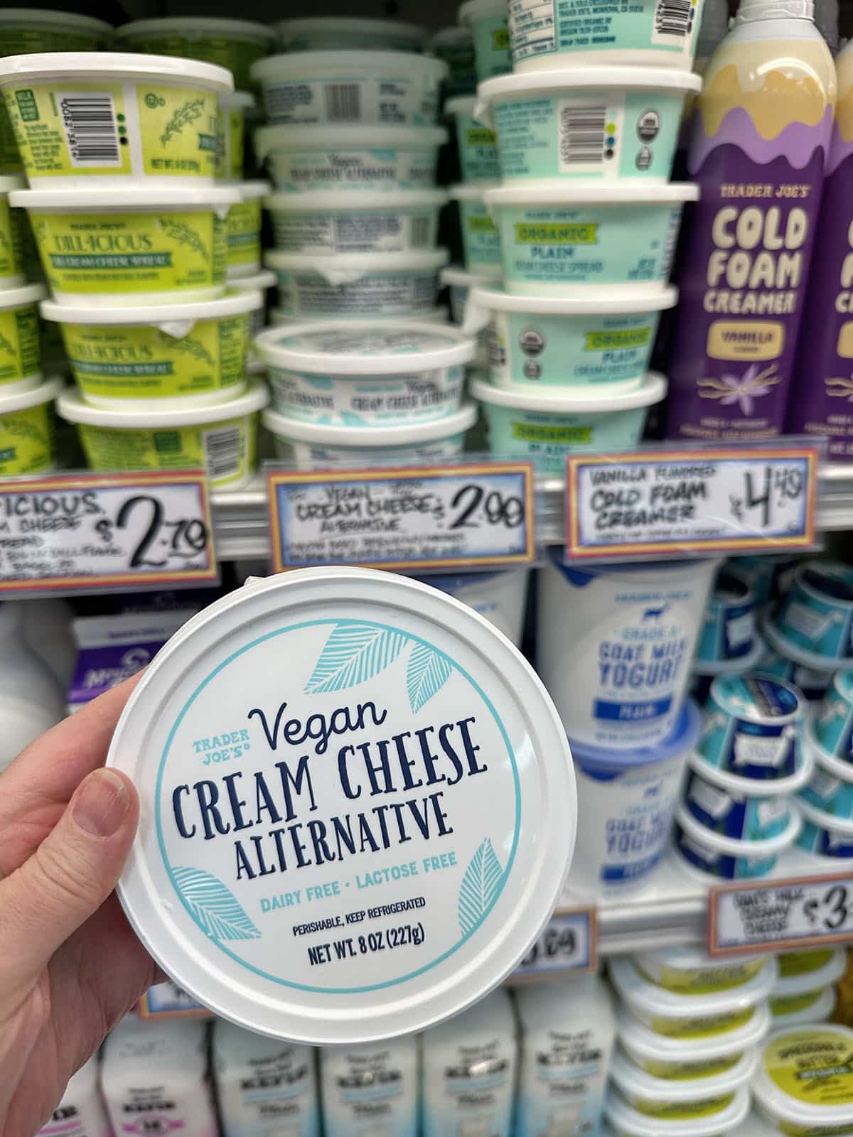 Hand holding container of vegan cream cheese alternative at Trader Joe's.