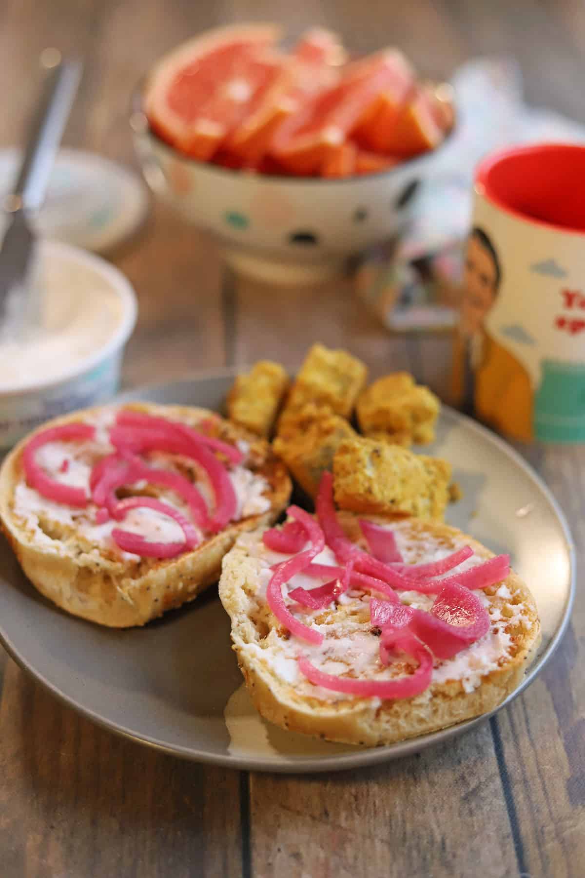 Trader Joe's vegan cream cheese on bagel with pickled red onions by tofu, coffee, and grapefruit.
