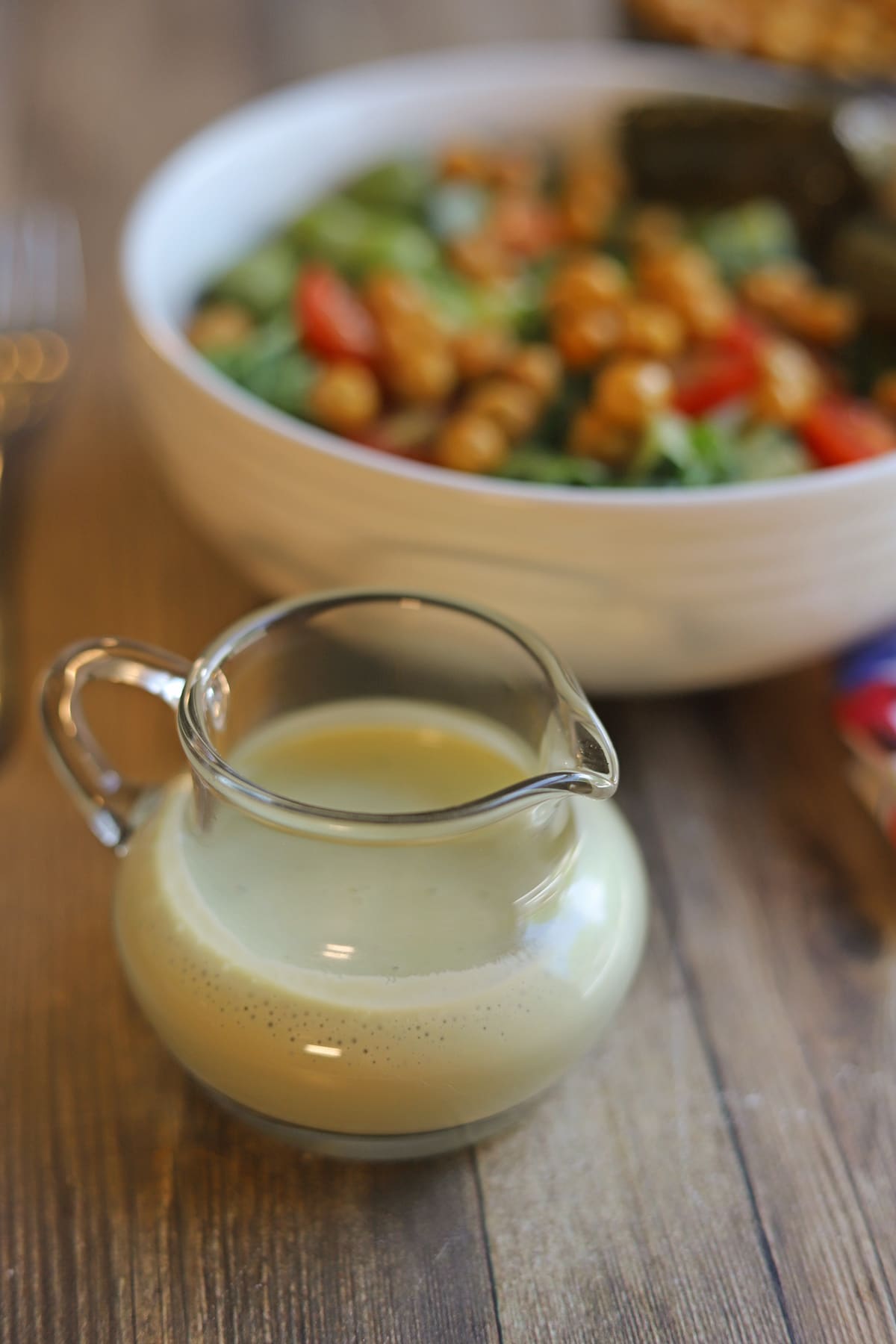 Small pitcher with cilantro cashew dressing in front of kale salad.