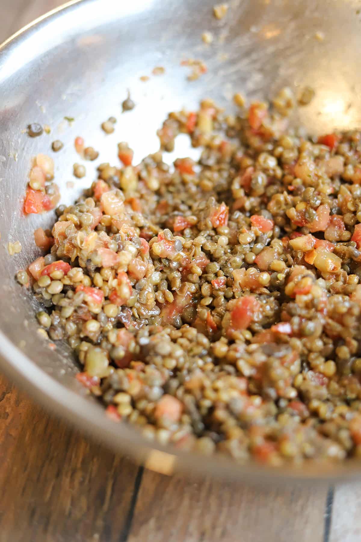 Bowl of steamed lentils mixed with bruschetta sauce.