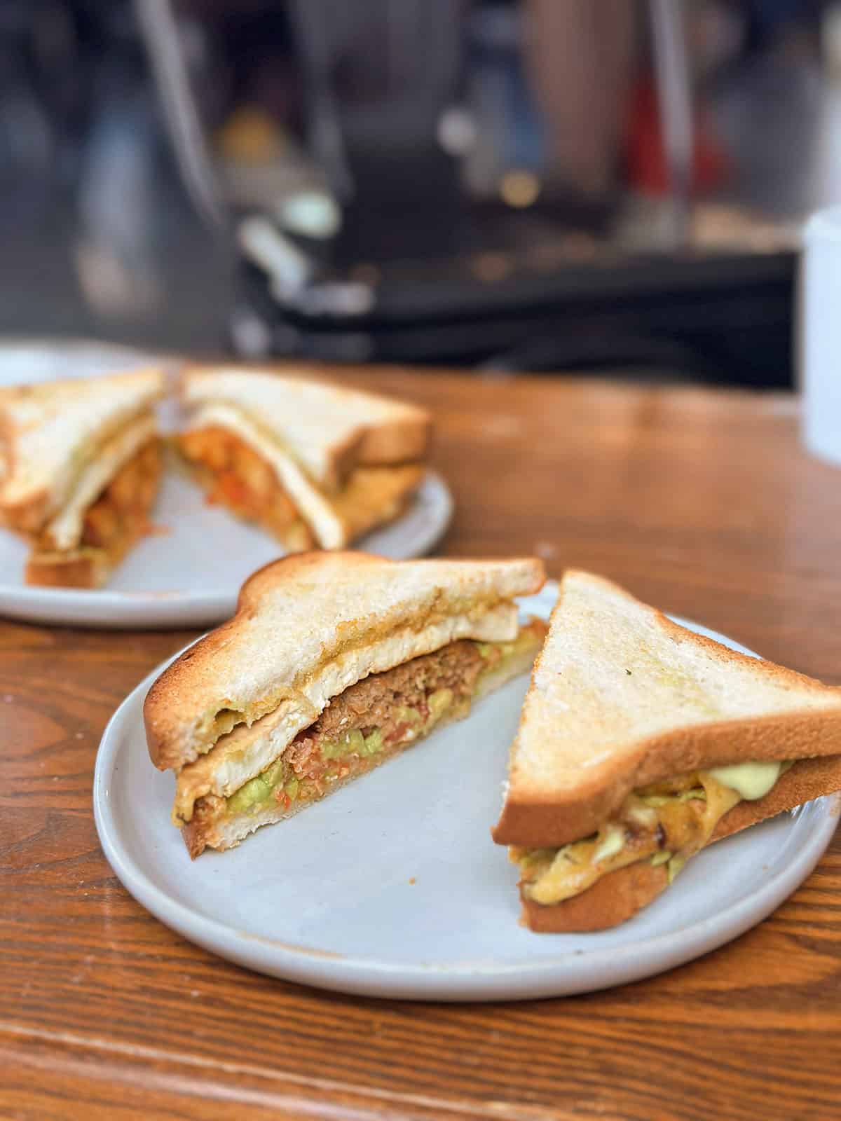 Vegan breakfast sandwich with tofu, vegan sausage, non-dairy cheese, and avocado.