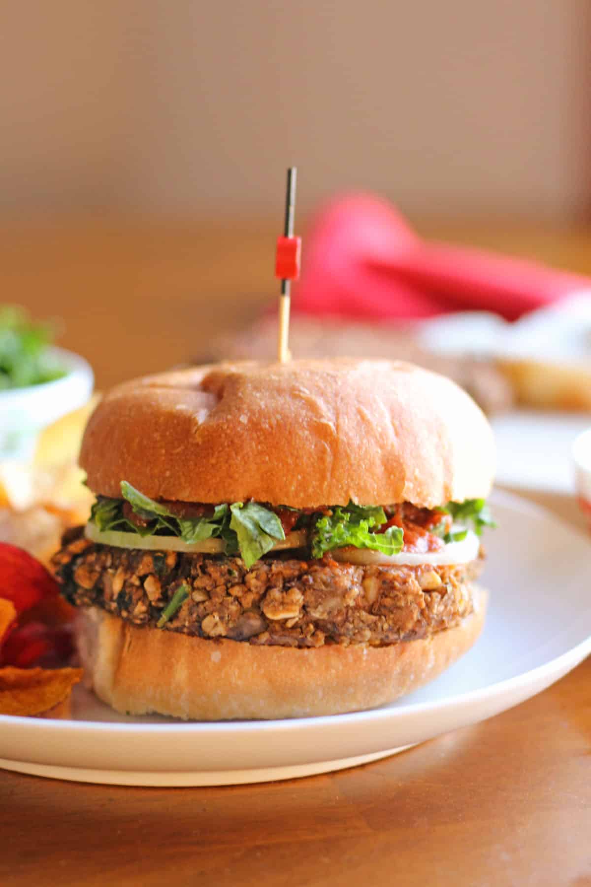 Meatball-flavored lentil burger on bun with kale, onion, and pasta sauce.