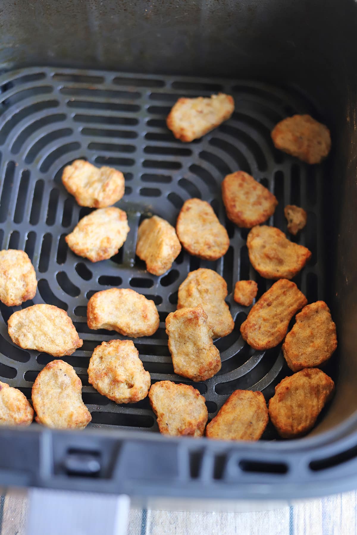 Vegan chicken morsels in air fryer basket.